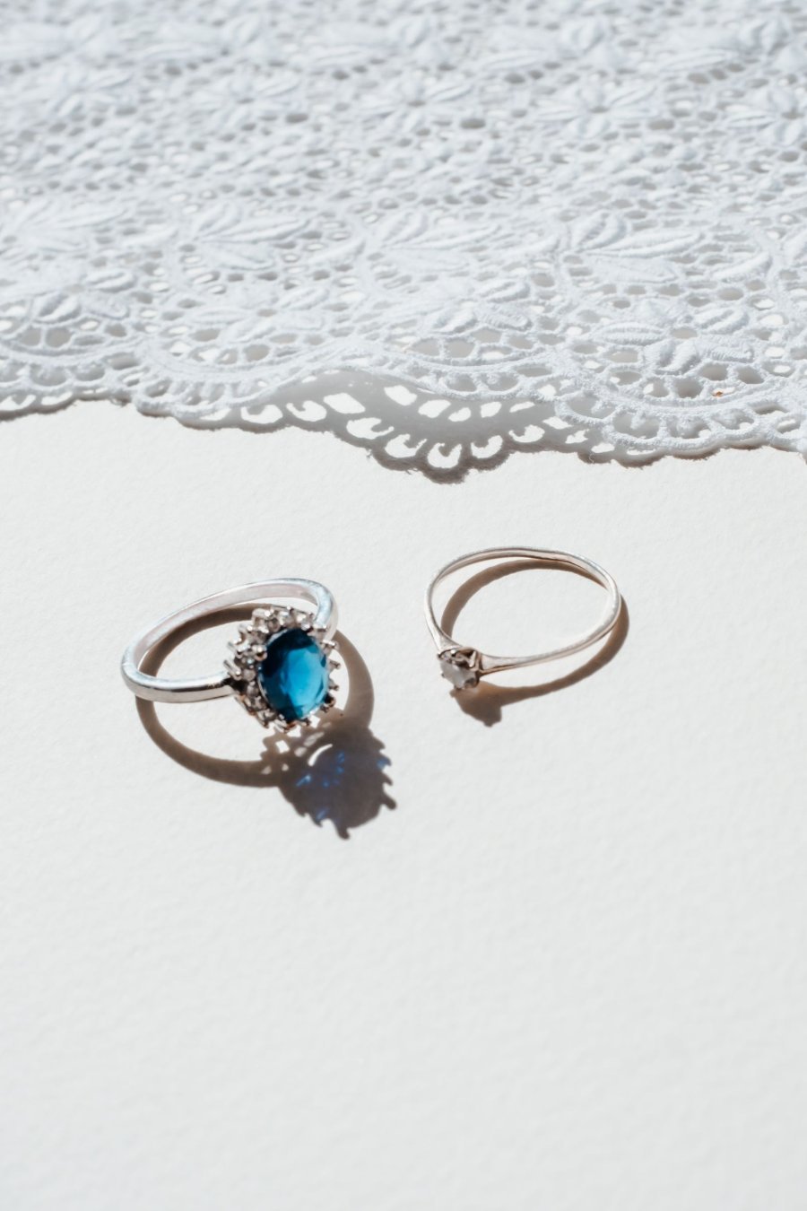 Two rings, one set with a blue stone, resting on white lace