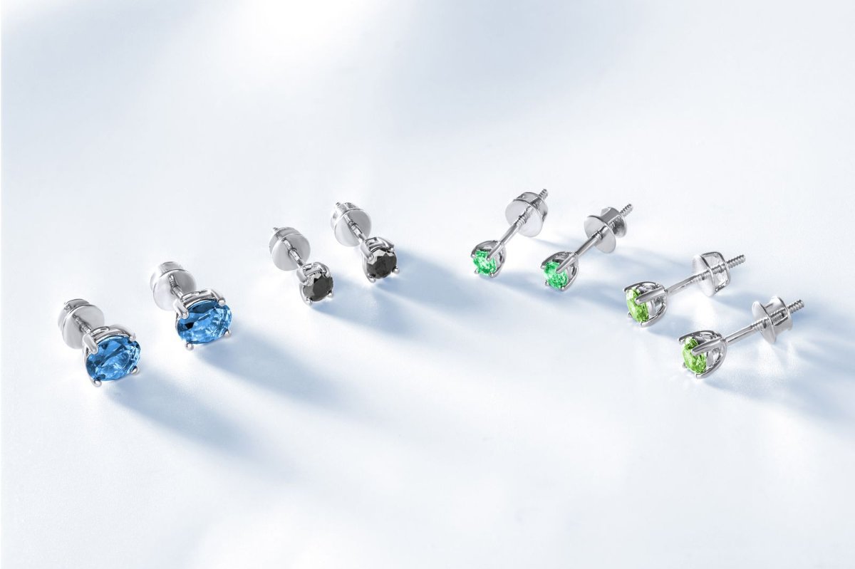 Stud earrings with colored stones lying on a white surface